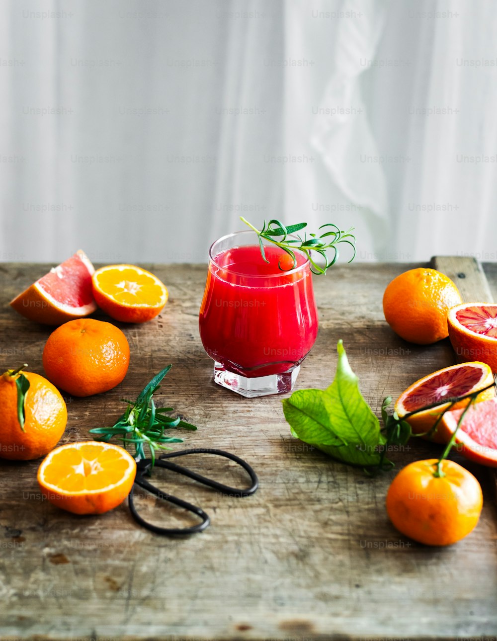 a wooden cutting board topped with oranges and a cup of juice