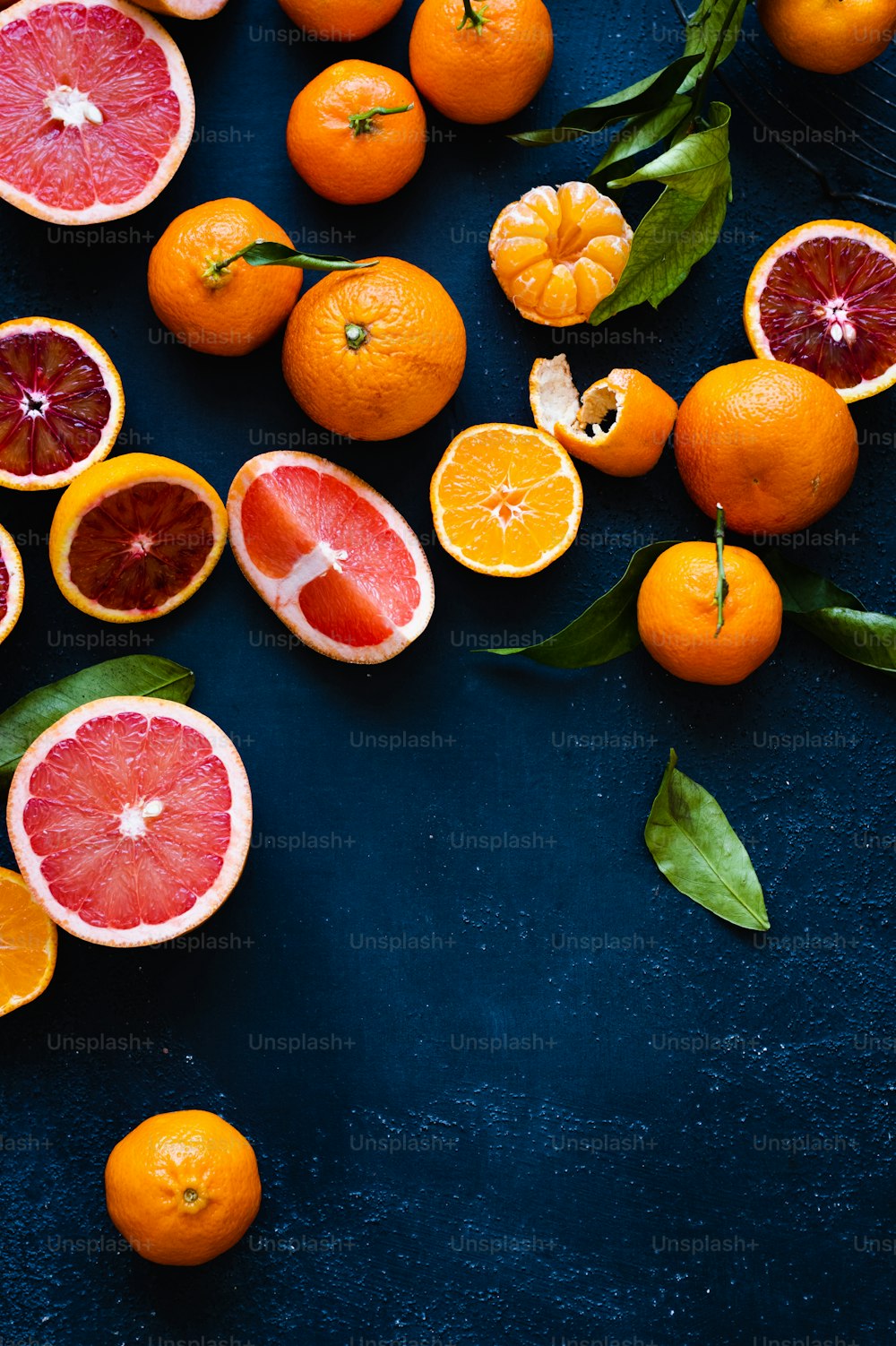 un gruppo di pompelmi e arance su una superficie blu