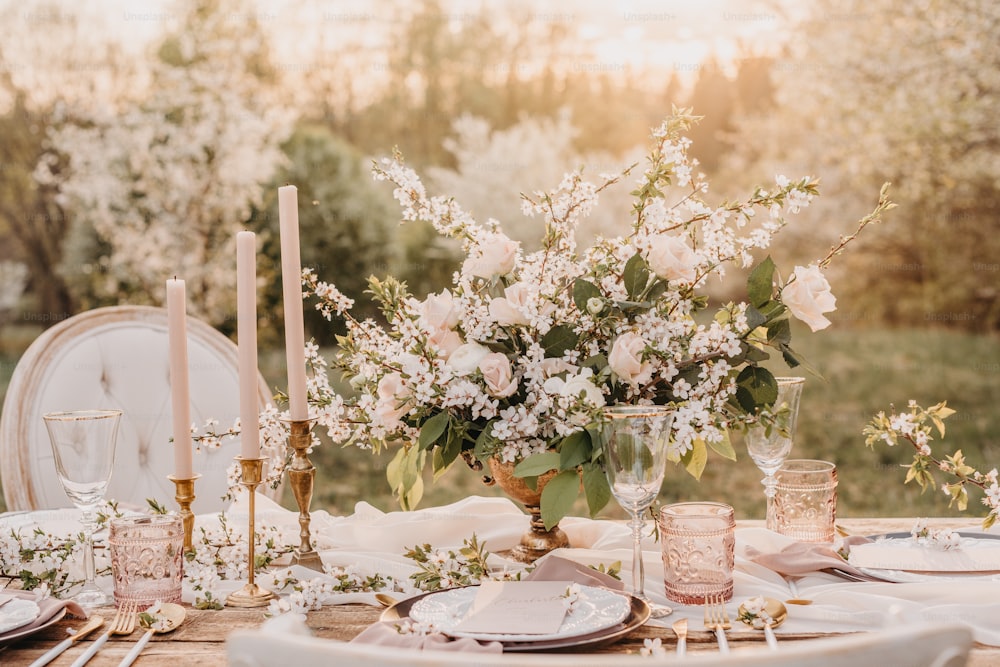 ein Tisch mit einer Vase mit Blumen und Kerzen darauf