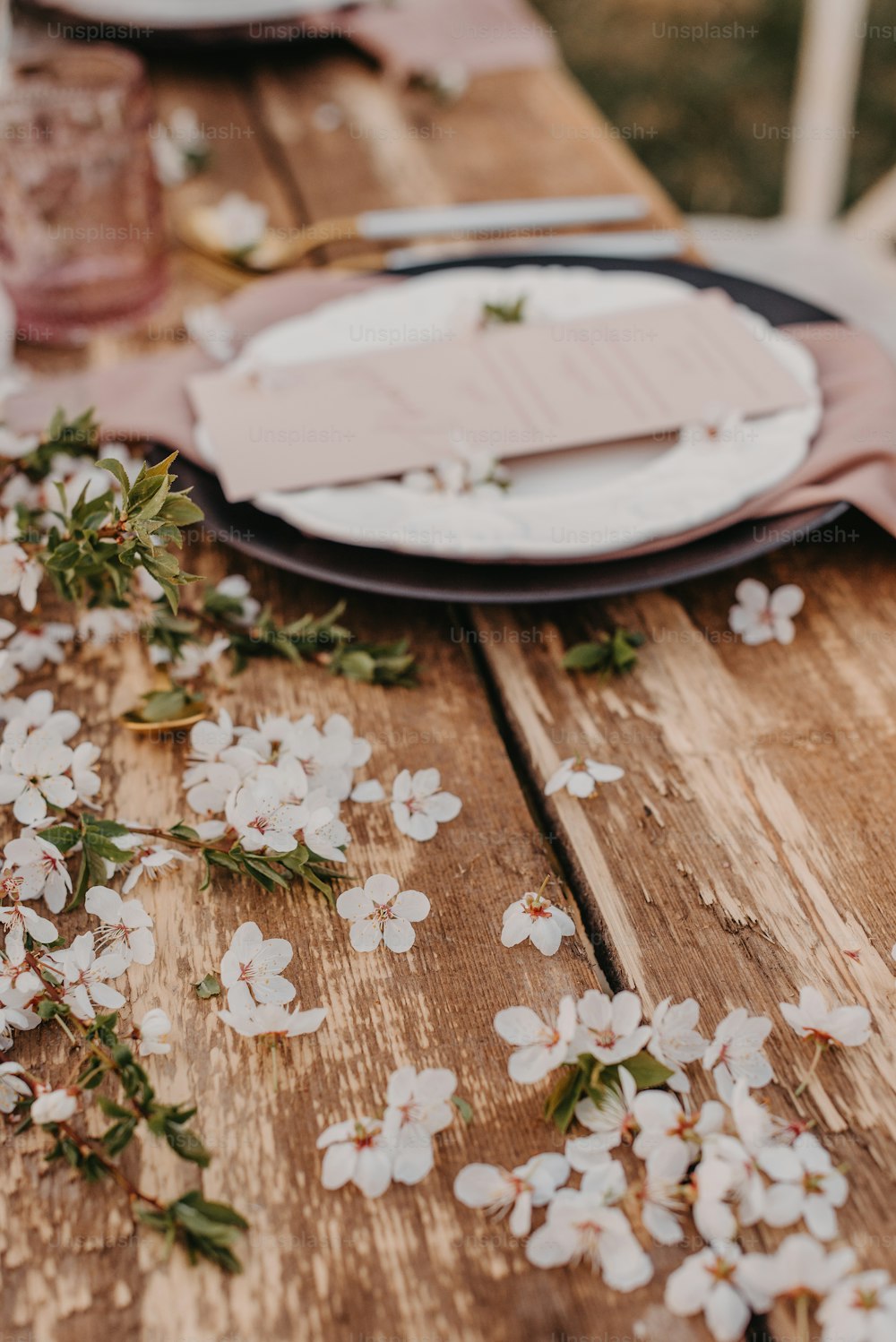 a wooden table topped with plates and flowers