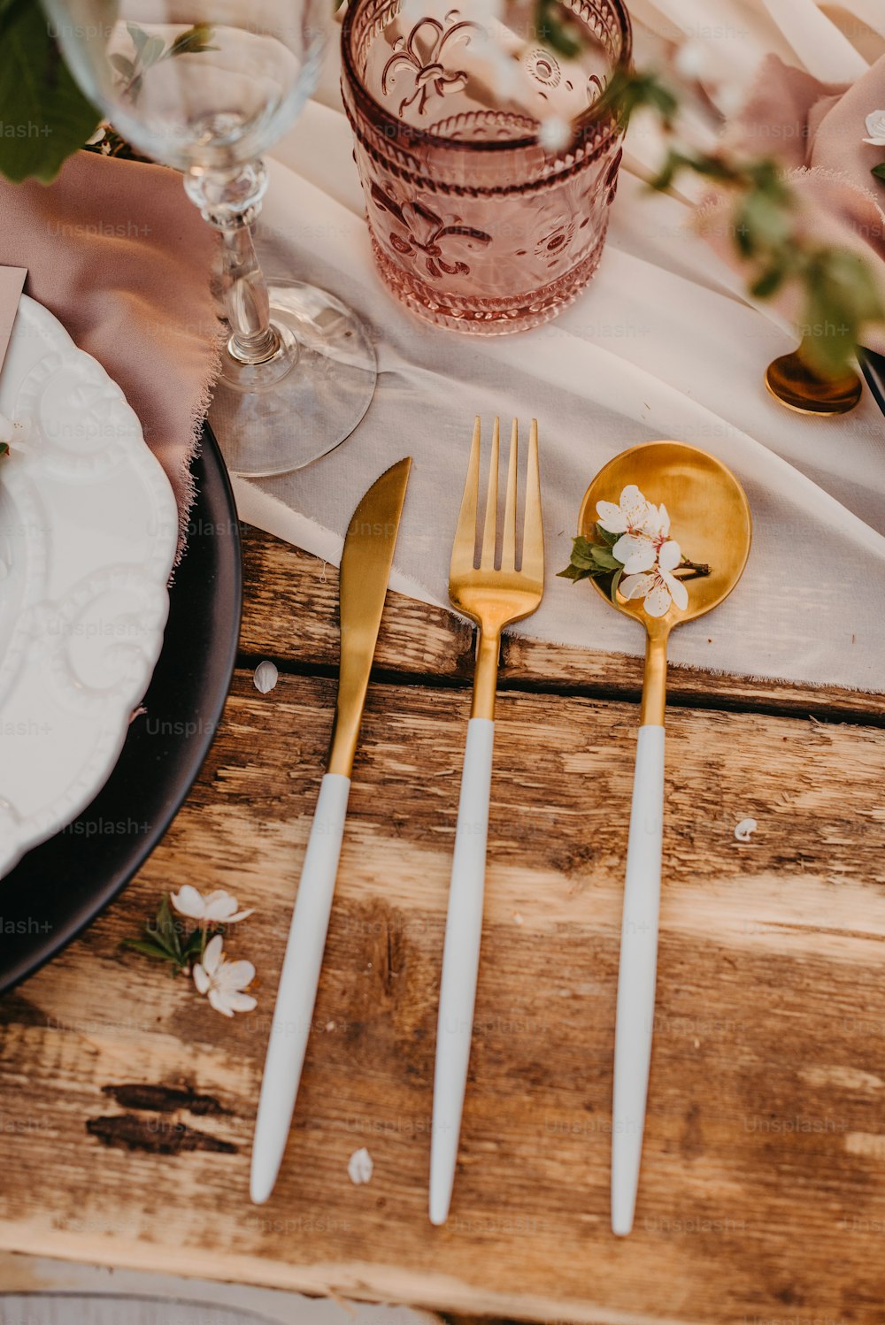 a wooden table topped with white and gold utensils