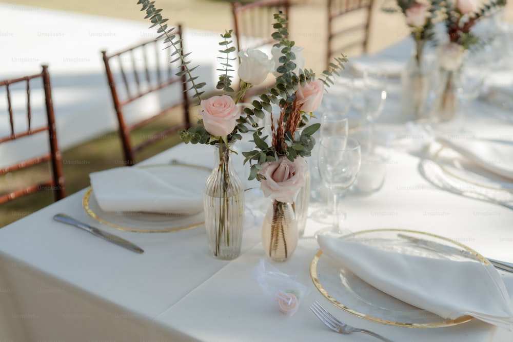 ein Tischset für eine Hochzeit mit Blumen in Vasen