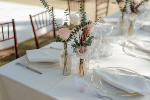 a table set for a wedding with flowers in vases