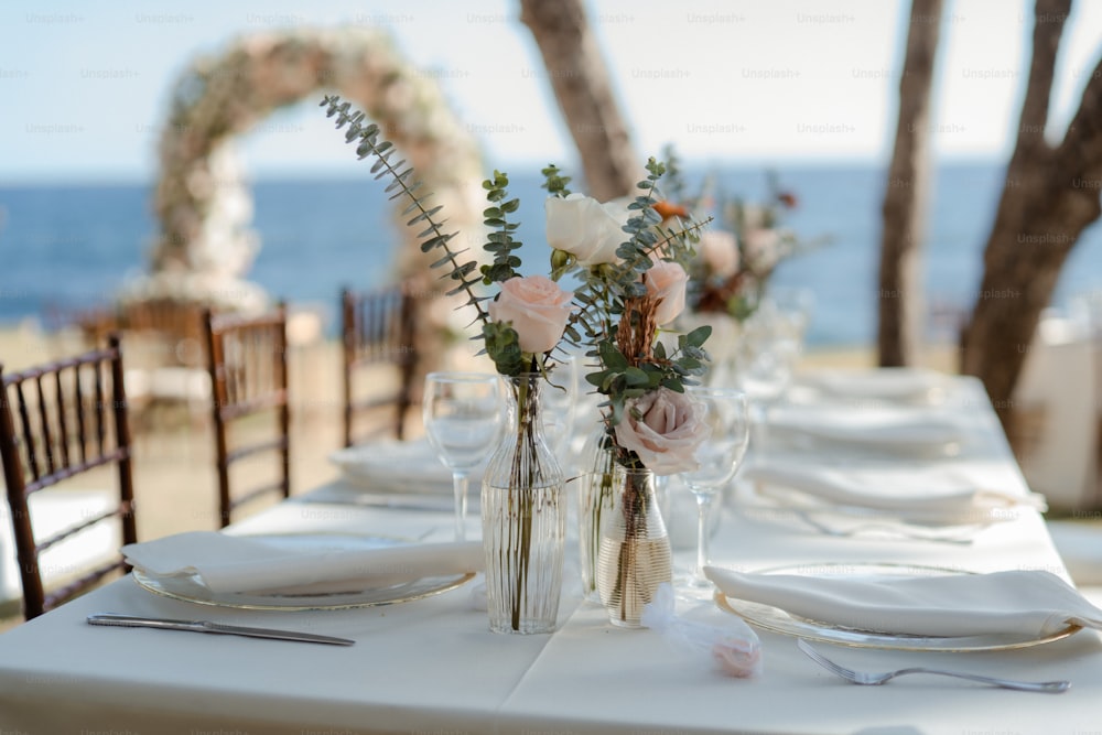 a table set for a wedding with flowers in vases