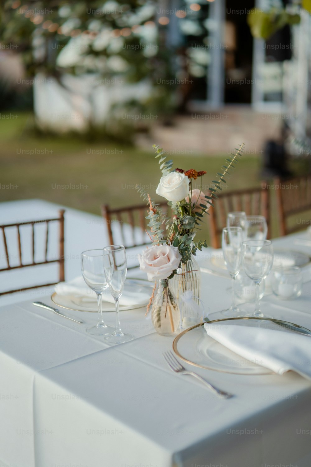 Una mesa puesta para una cena formal con flores en un jarrón