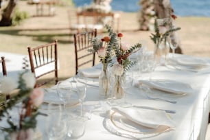 a table set for a wedding with flowers in a vase
