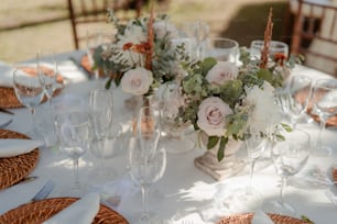 uma mesa branca coberta com muitos copos e flores