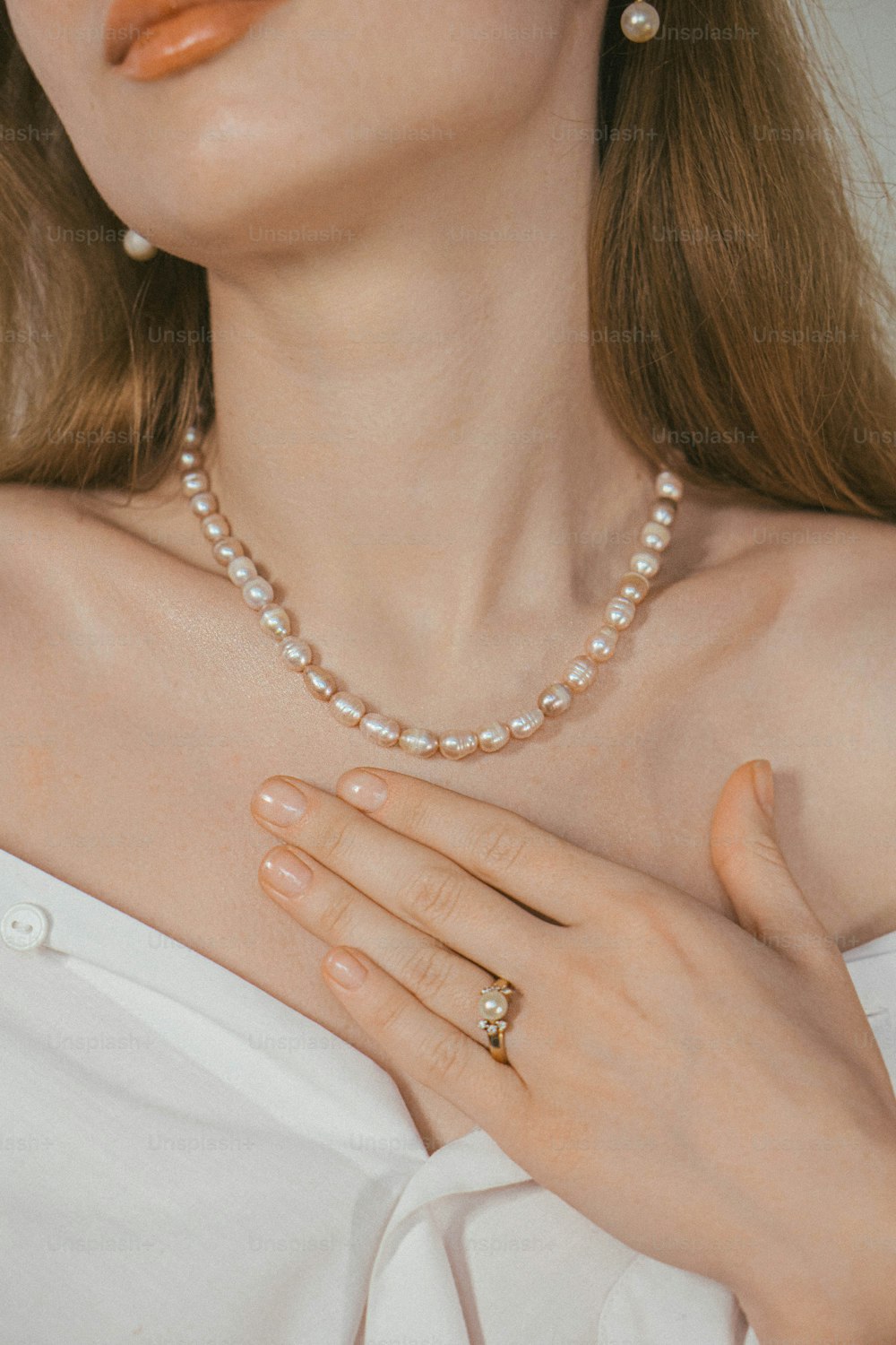 Eine Frau trägt eine Perlenkette und einen Ring