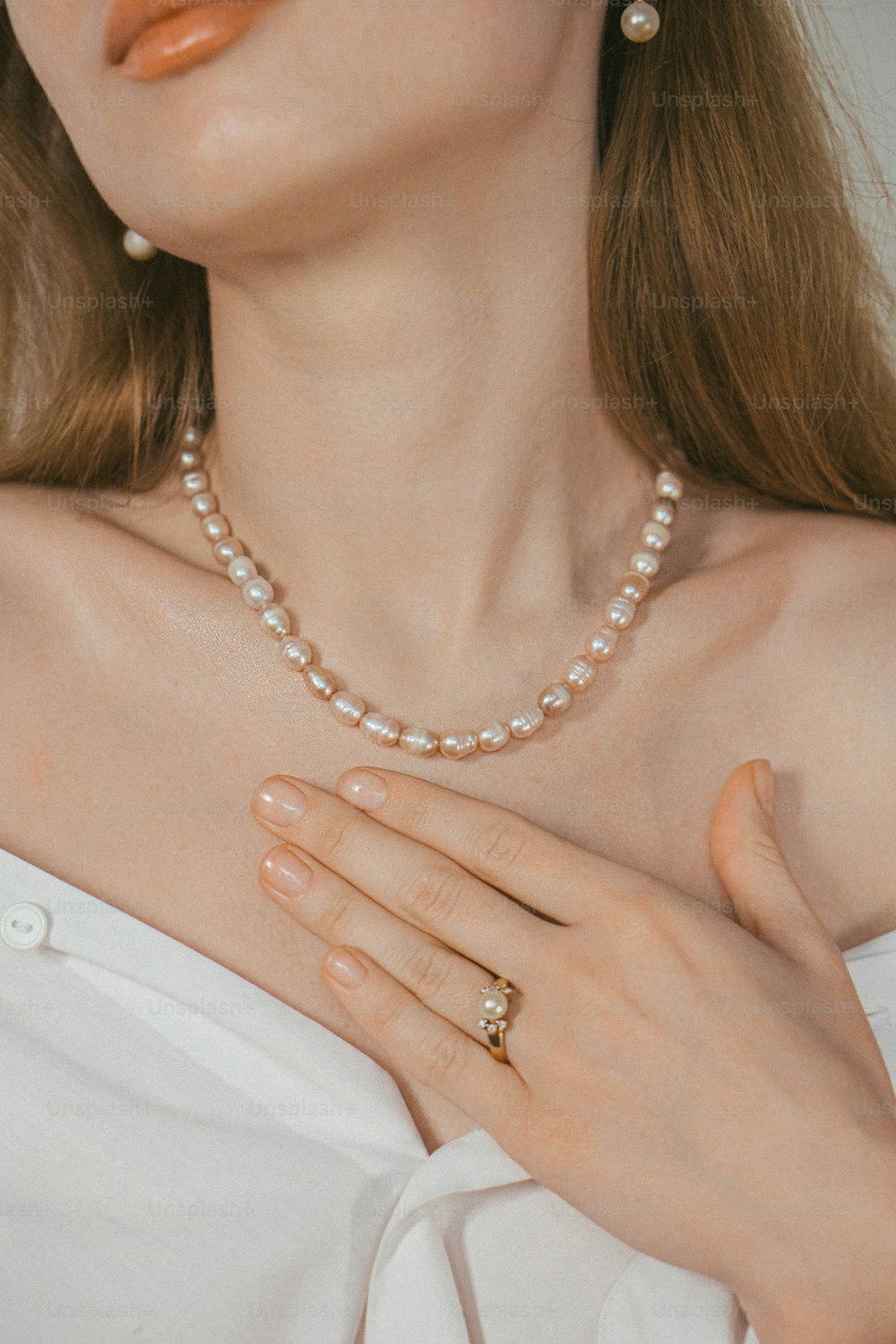a woman wearing a pearl necklace and ring
