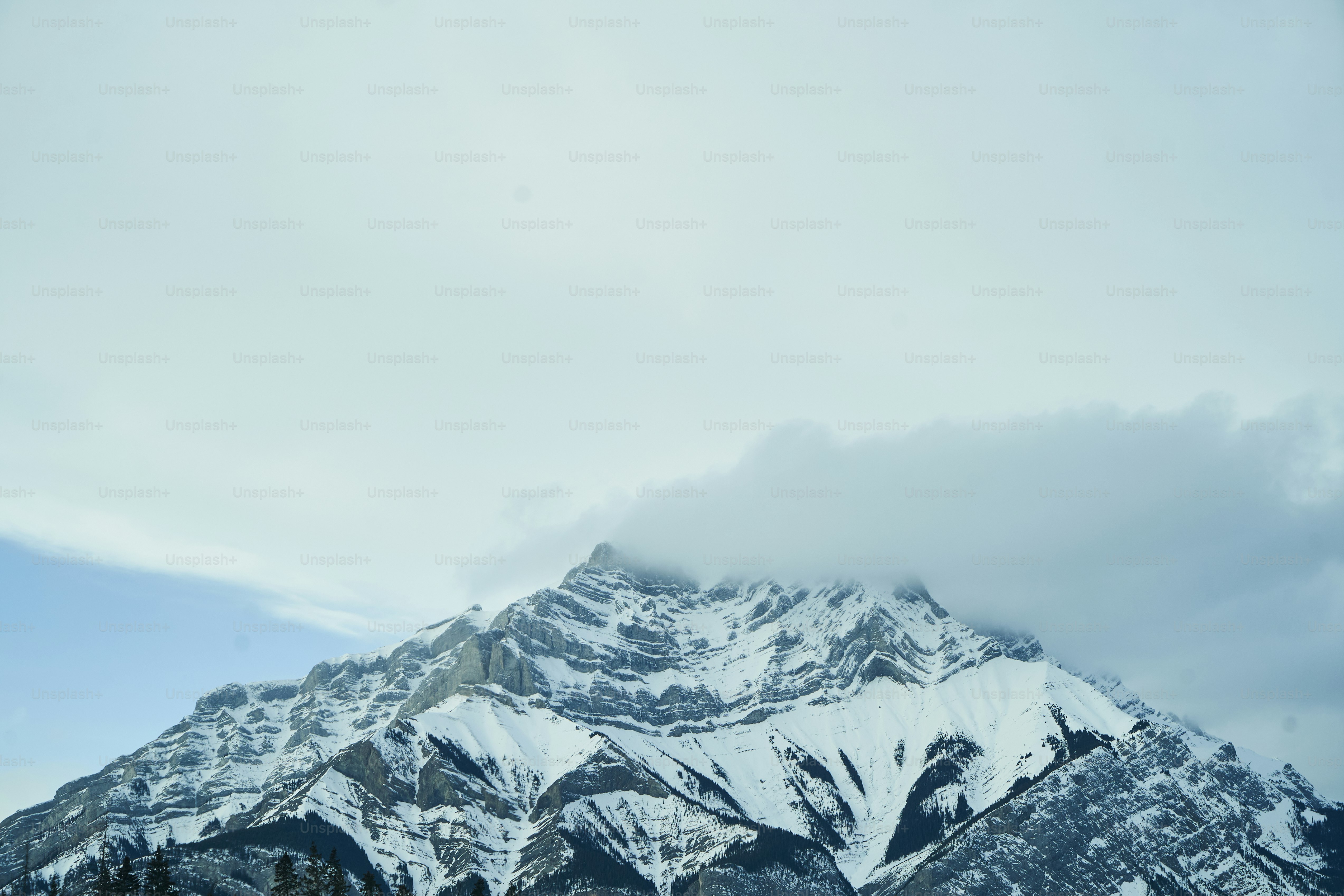 a mountain covered in snow under a cloudy sky