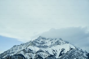 a mountain covered in snow under a cloudy sky