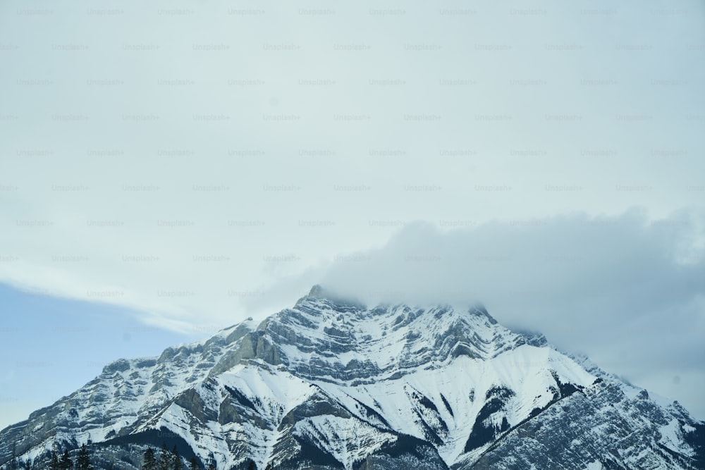 a mountain covered in snow under a cloudy sky