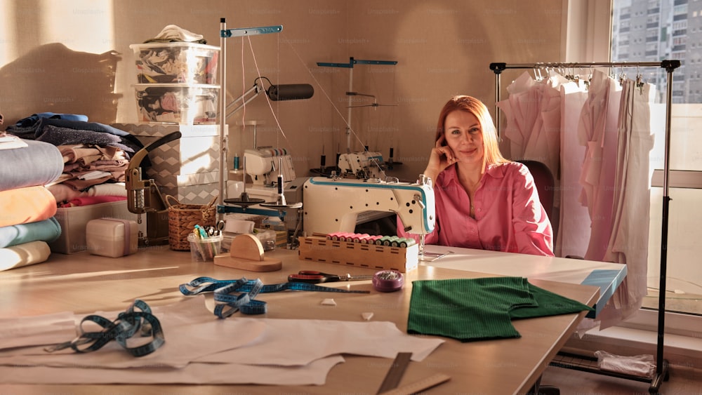 uma mulher sentada em uma mesa com uma máquina de costura