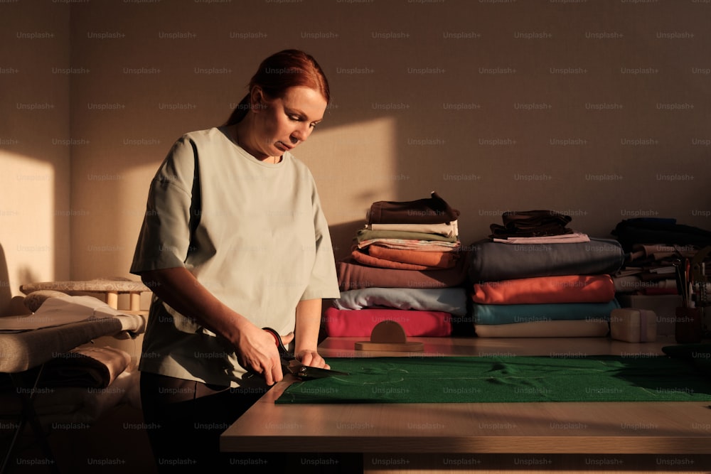 a woman standing in front of a table cutting fabric
