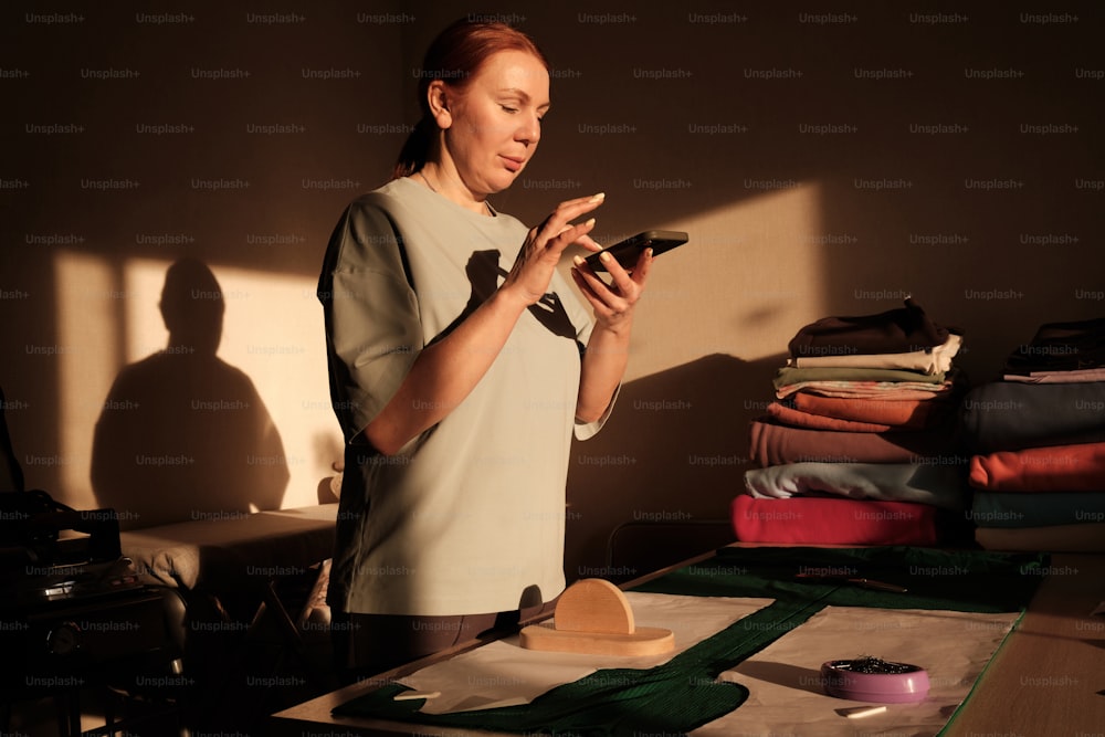 a woman standing in front of a table holding a cell phone