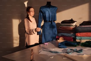 a woman standing next to a table with a dress on it