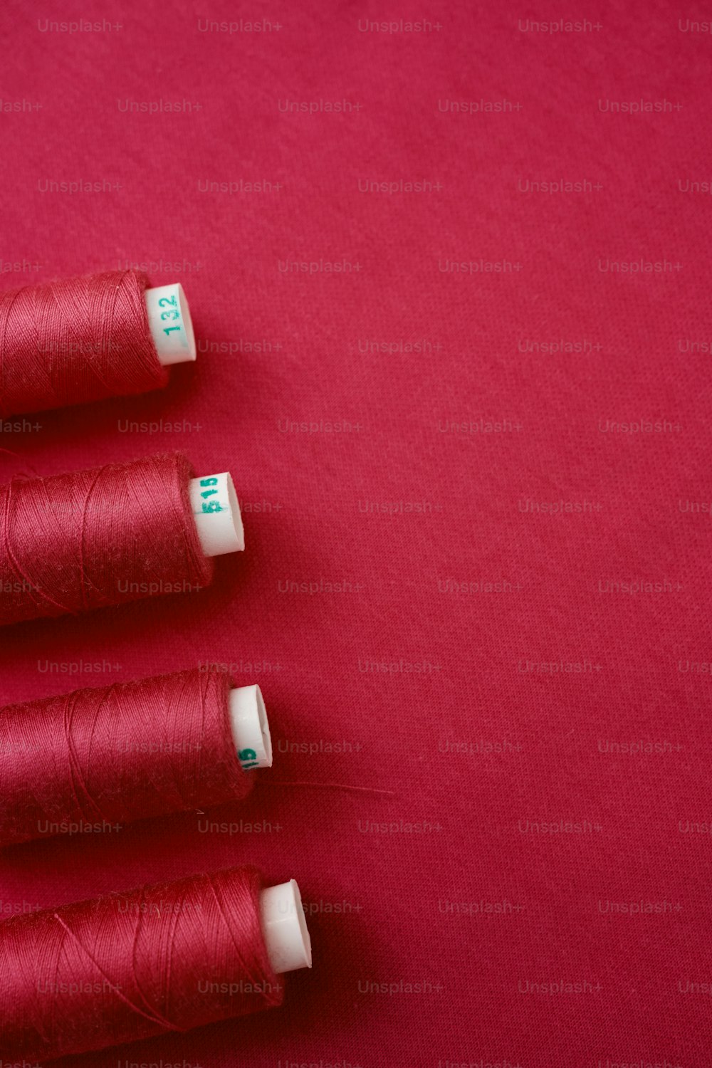 three spools of thread on a red surface