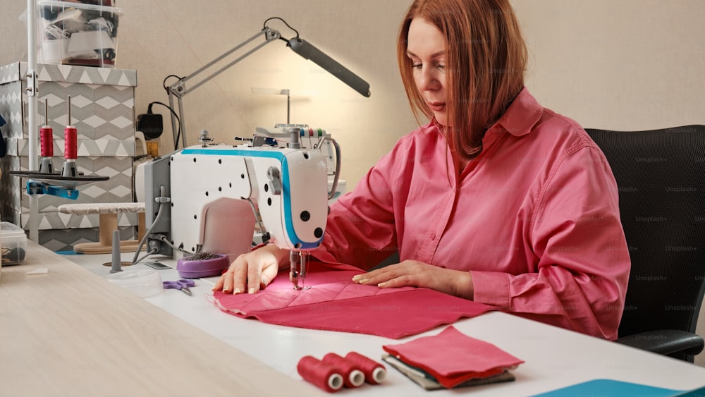 a woman in a pink shirt is working on a sewing machine