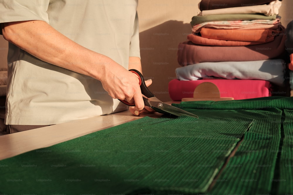a person cutting fabric with a pair of scissors