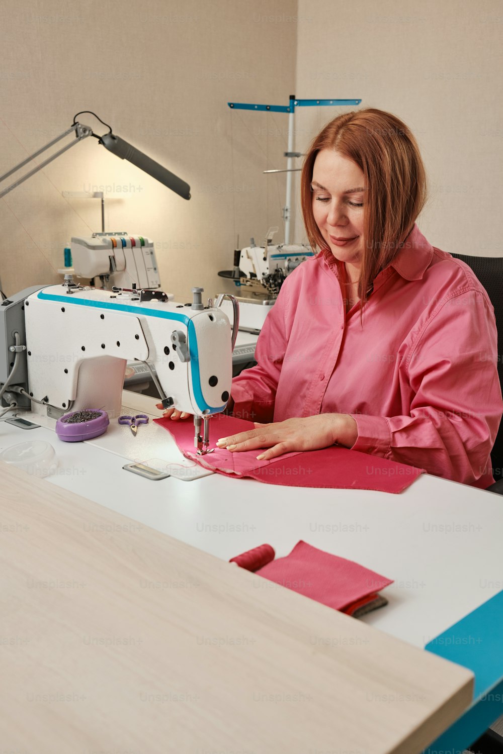 uma mulher sentada em uma mesa com uma máquina de costura