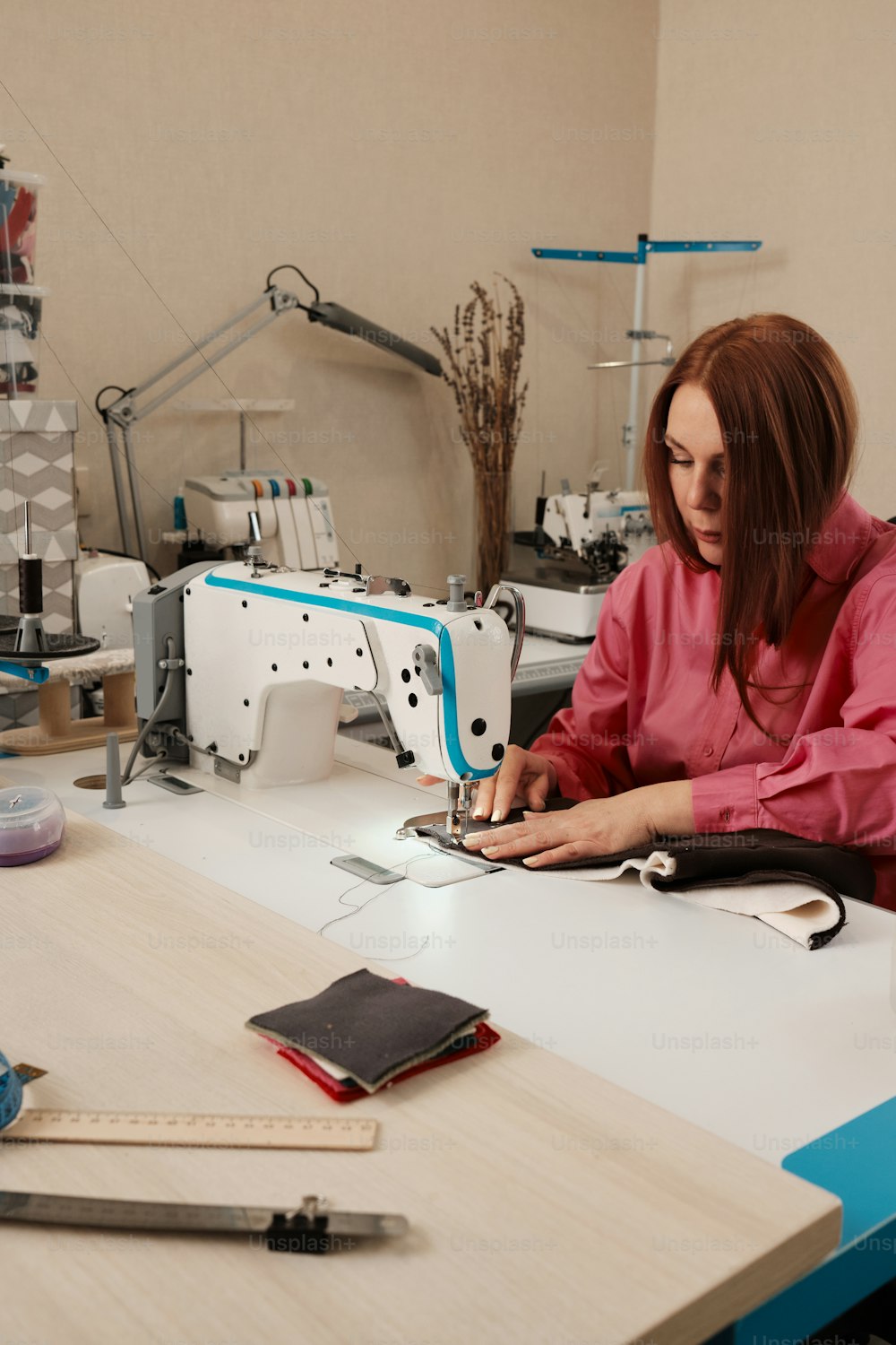 uma mulher sentada em uma máquina de costura que trabalha em um pedaço de tecido