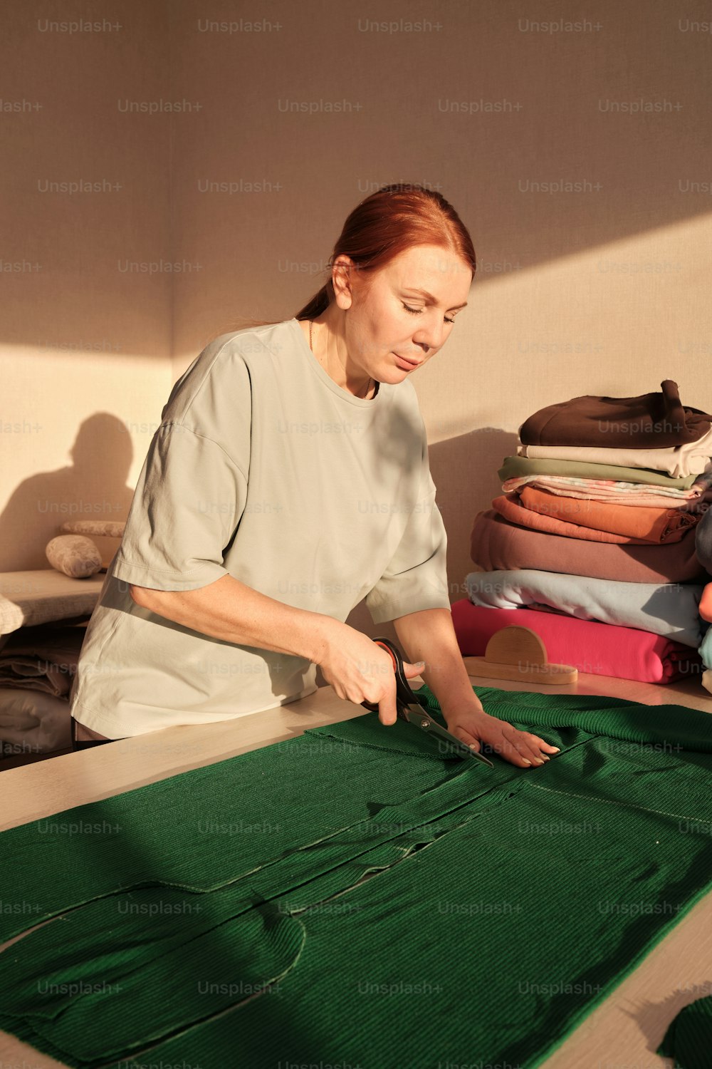 a woman is working on a green piece of cloth