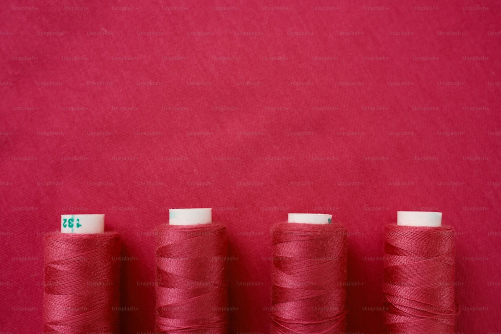 three spools of red thread on a red background