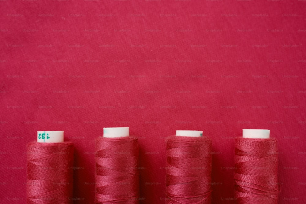 three spools of red thread on a red background