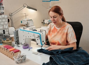 a woman sitting at a desk working on a sewing machine
