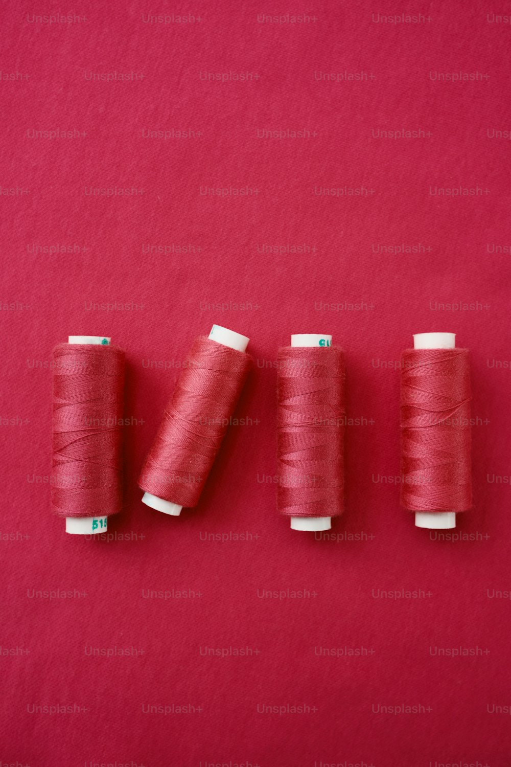 drei Fadenspulen auf rotem Hintergrund
