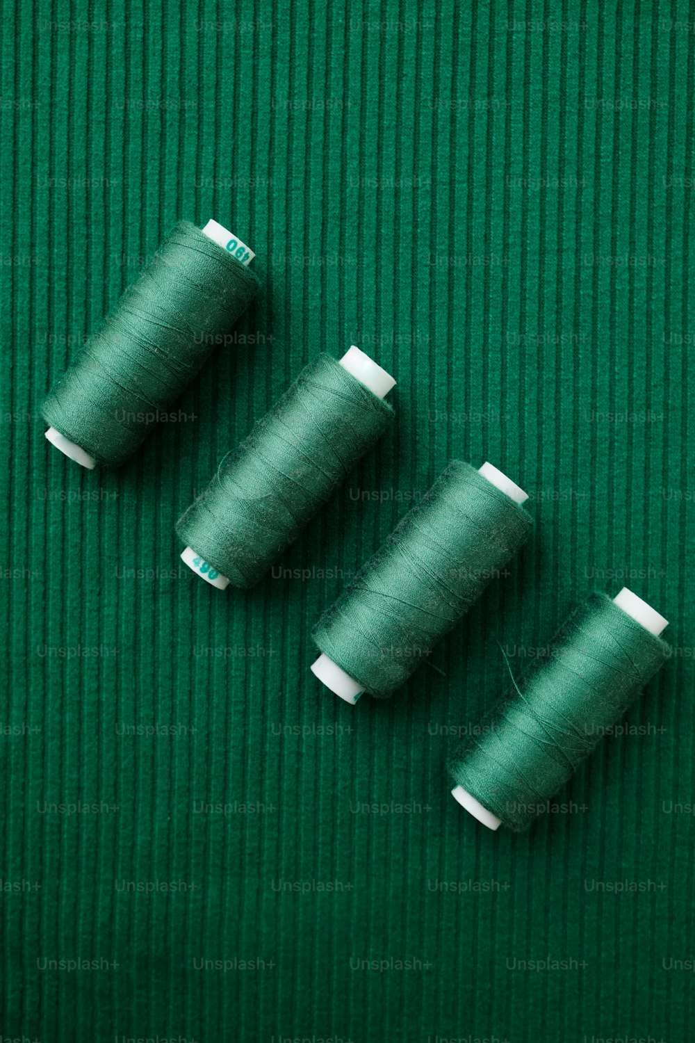 três carretéis de fio sentados em uma superfície verde
