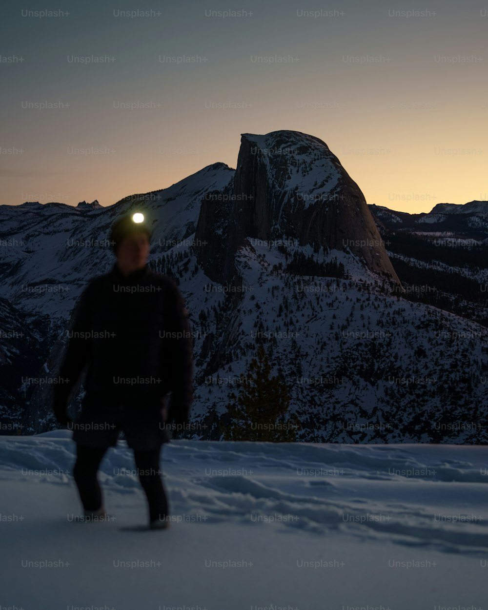 Un hombre parado en la cima de una ladera cubierta de nieve