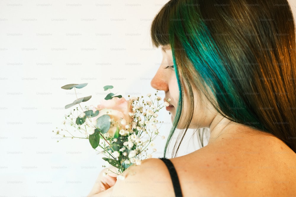 uma mulher com cabelo verde segurando um buquê de flores