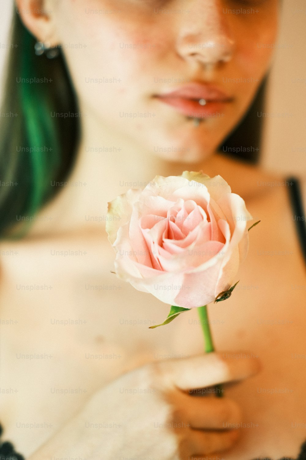 a woman holding a pink rose in her hand