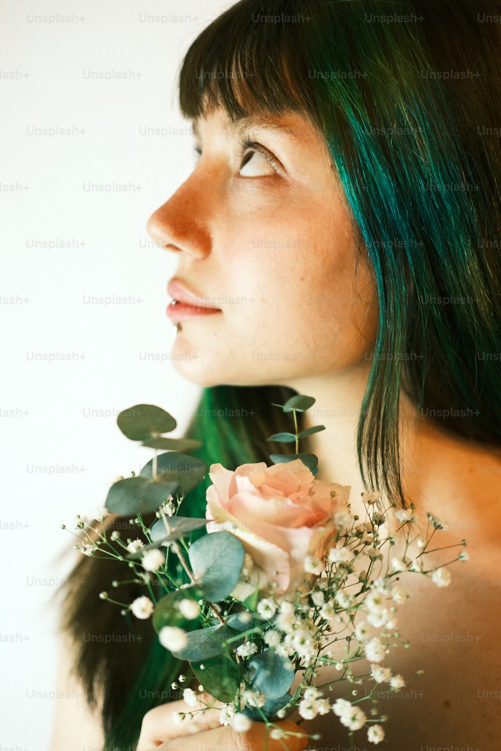 Une femme aux cheveux verts tenant un bouquet de fleurs