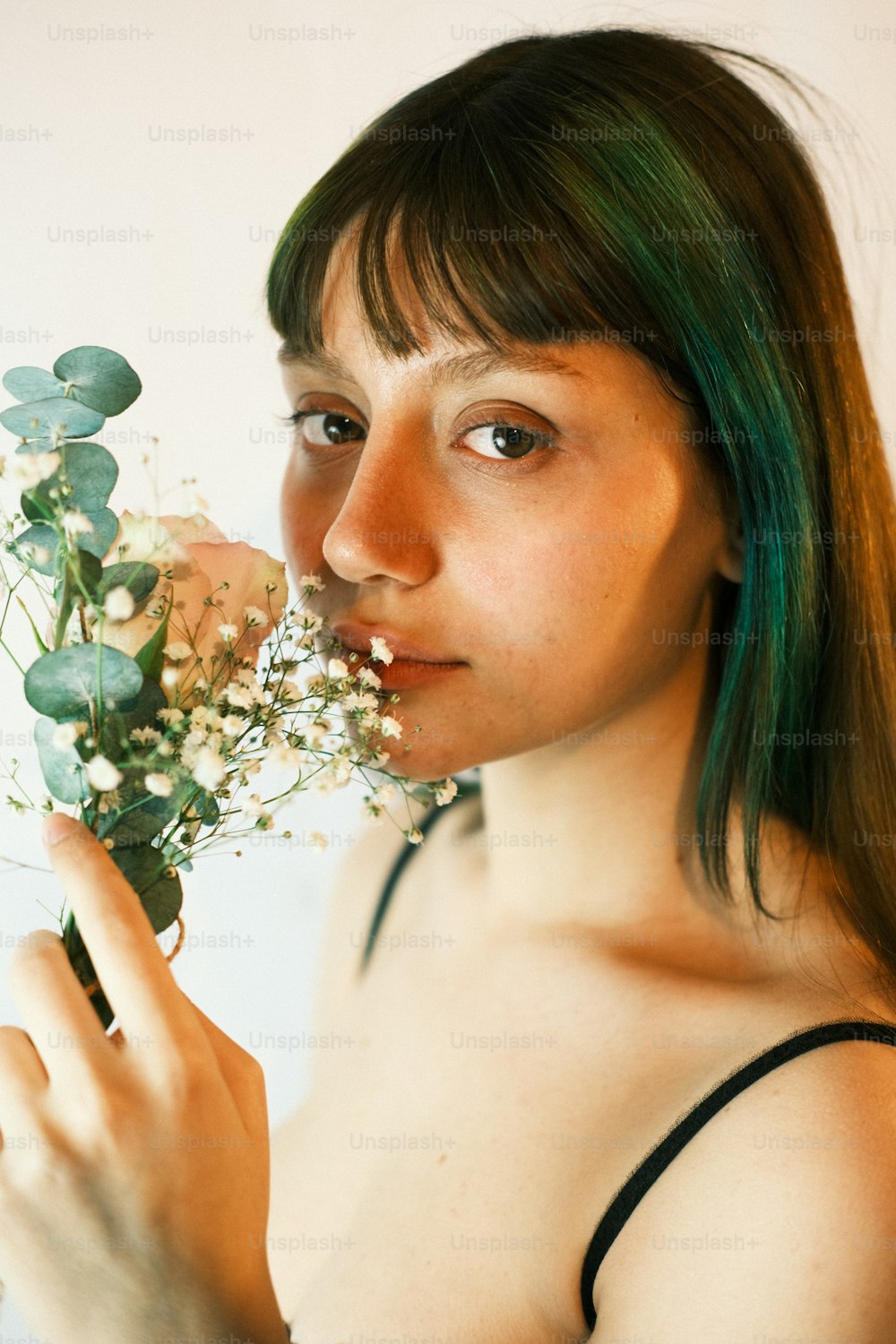 a woman with green hair holding a bunch of flowers