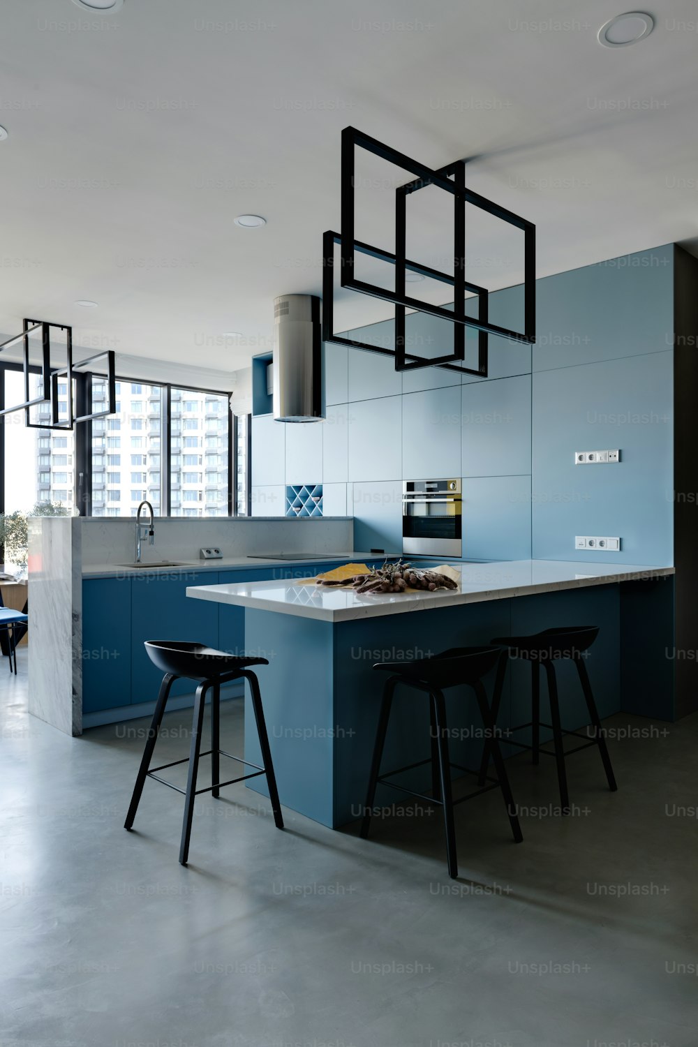 a modern kitchen with a blue island and black stools