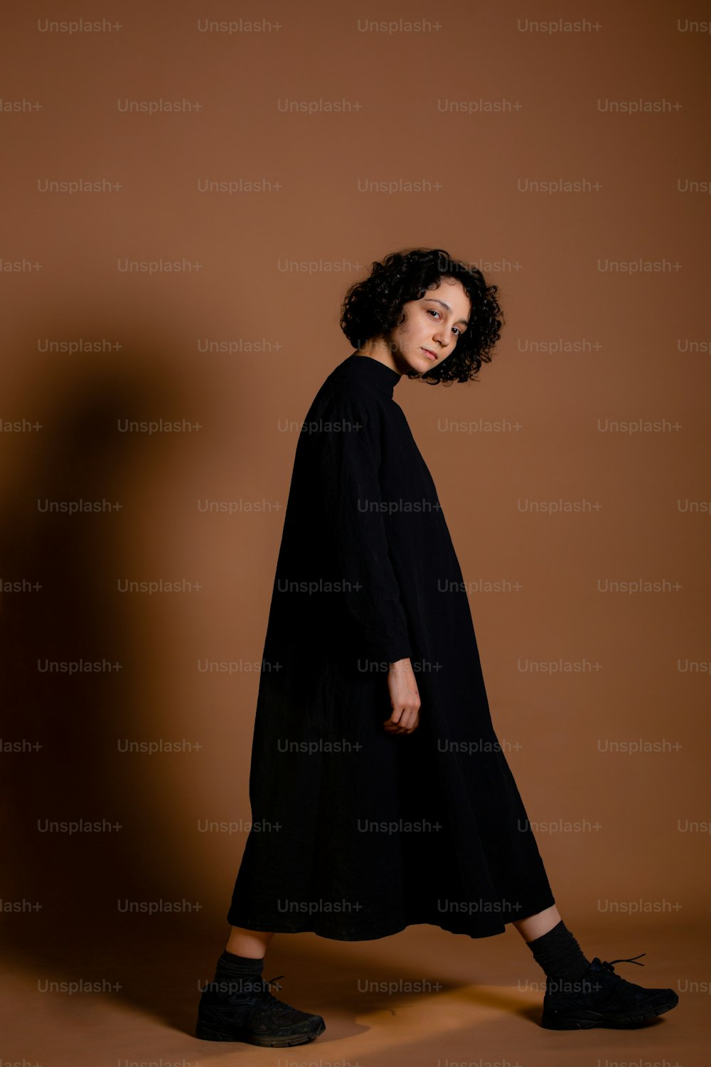 a woman standing in front of a brown background