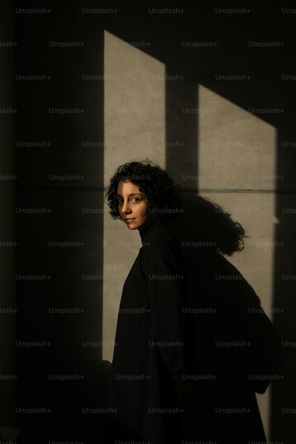 Una mujer de pie en las sombras de una pared