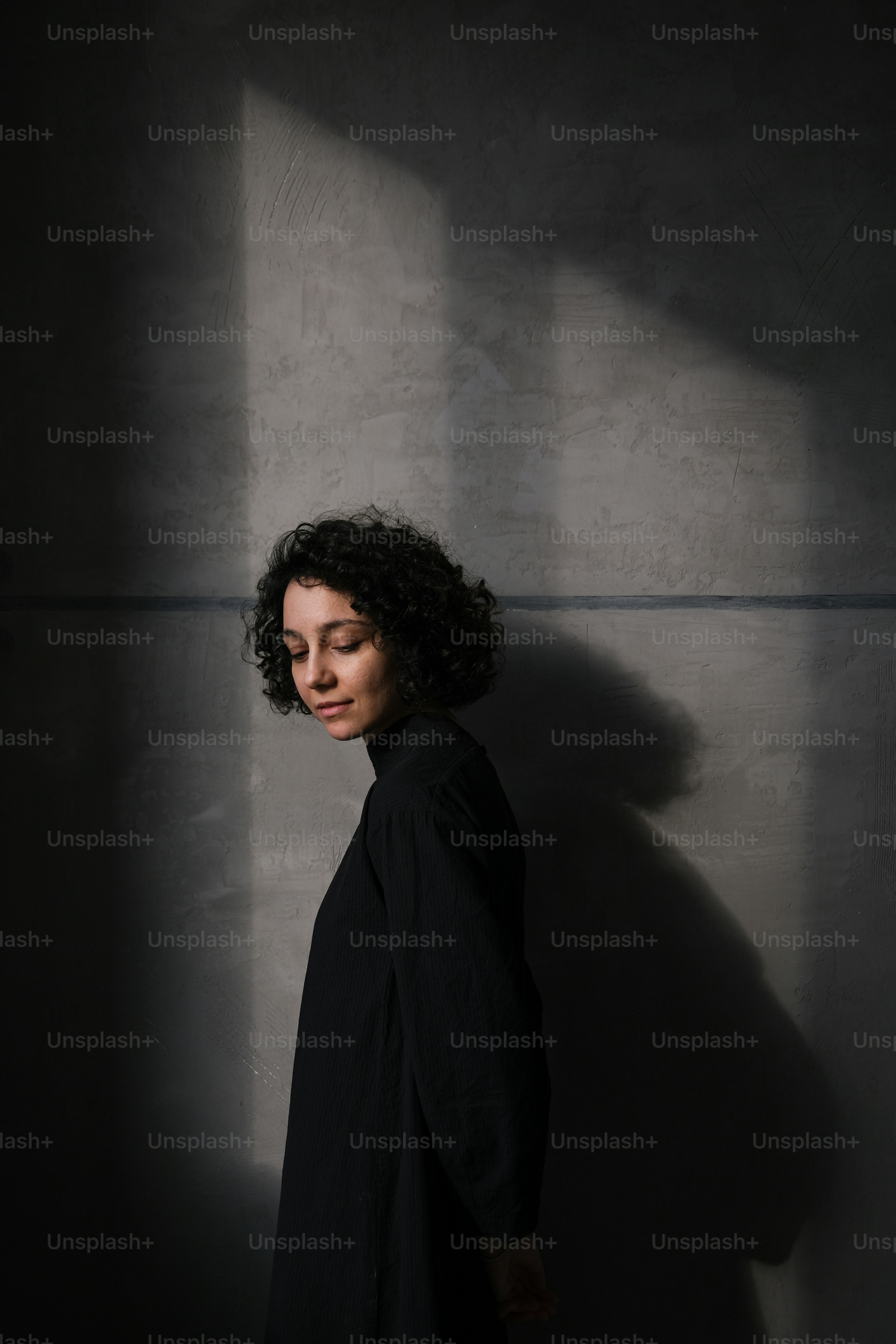 Una donna in piedi all'ombra di un muro