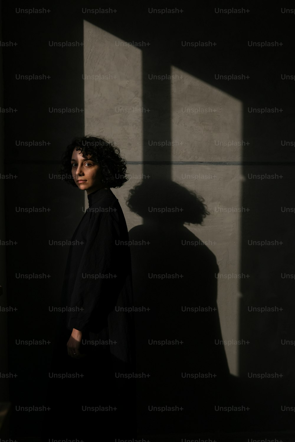 a woman standing in the shadows of a wall
