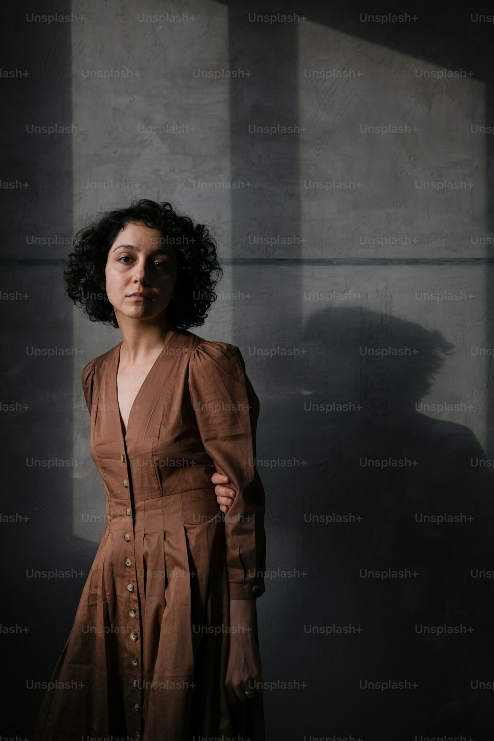 a woman in a brown dress standing in a dark room