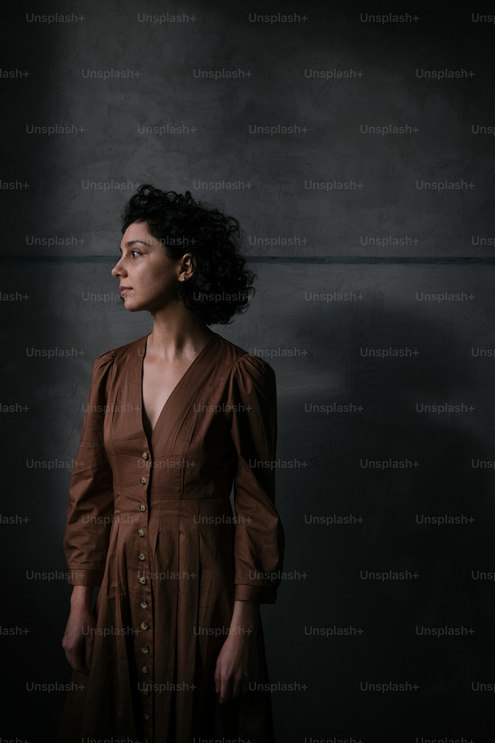 a woman in a brown dress standing in a dark room
