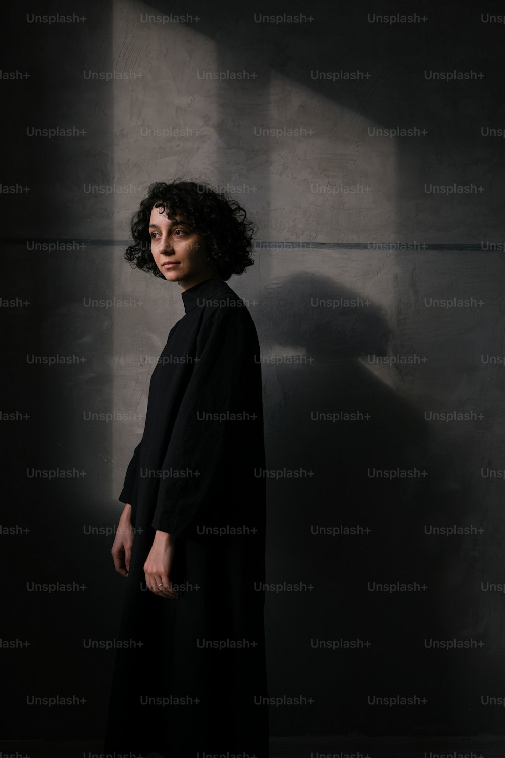 uma mulher em pé em um quarto escuro com uma sombra na parede