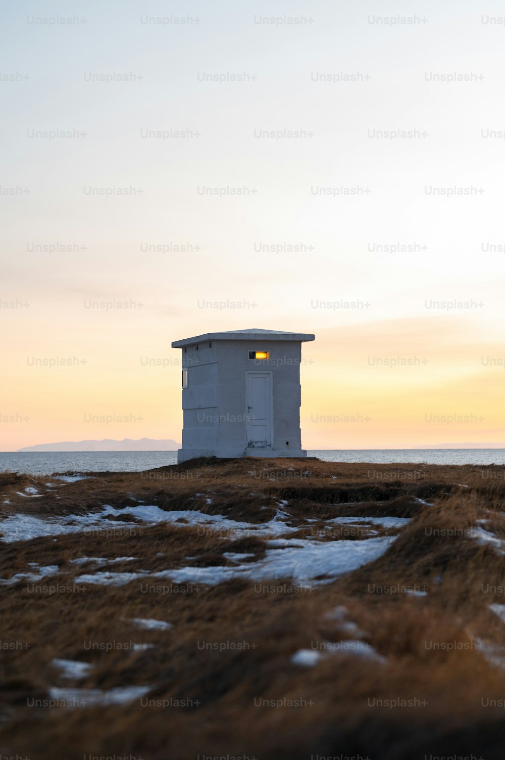 a small white building sitting on top of a snow covered field