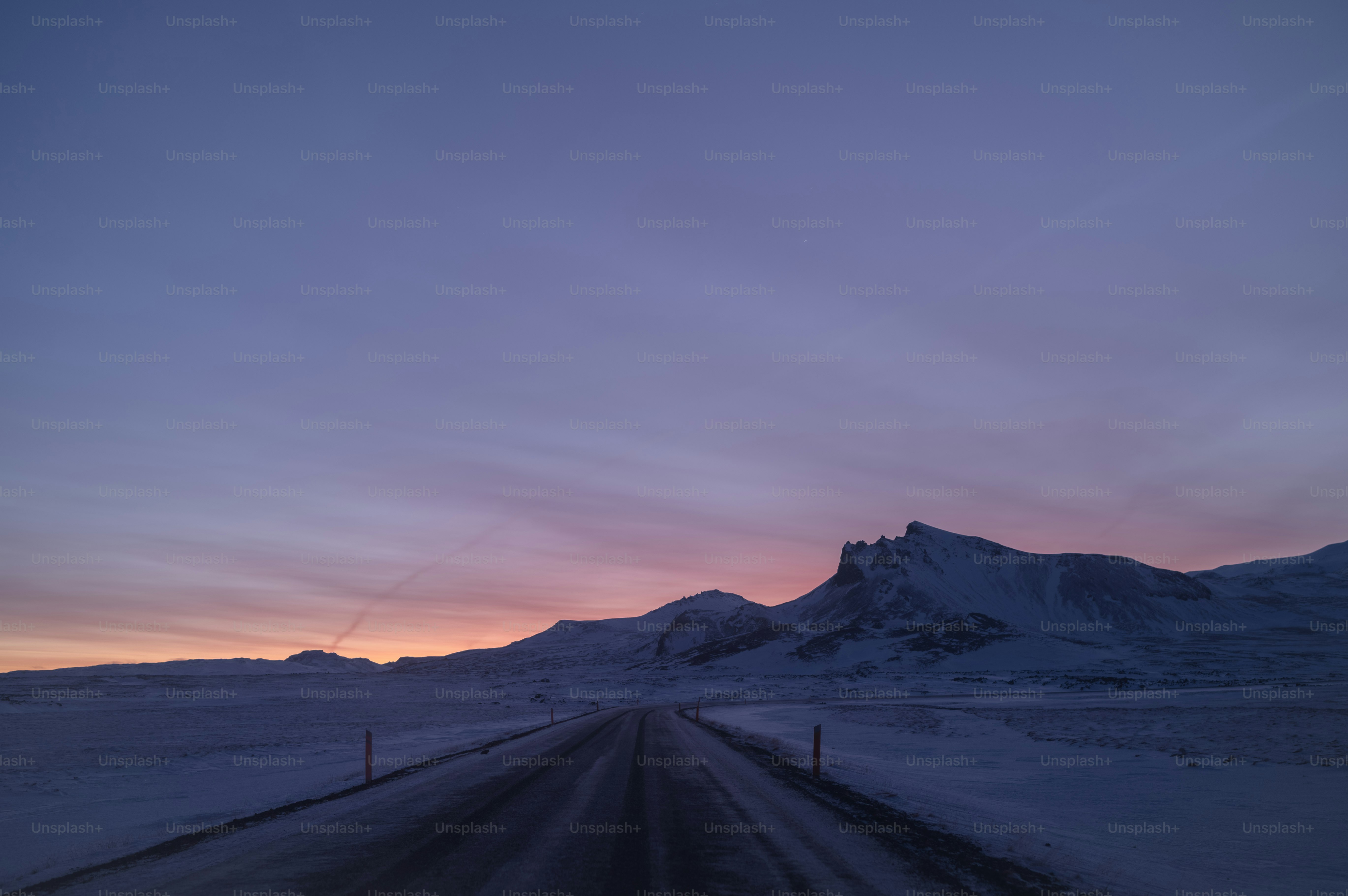 the sun is setting over a snowy mountain range