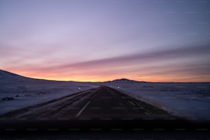 o sol está se pondo em uma estrada nevada
