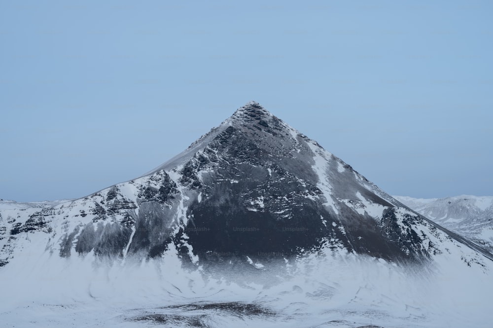 A snow covered mountain with a blue sky in the background photo