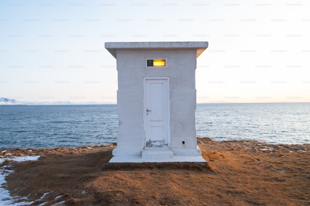 a white outhouse sitting on top of a sandy beach