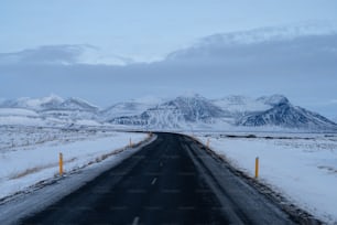 a road with snow on the ground and mountains in the background